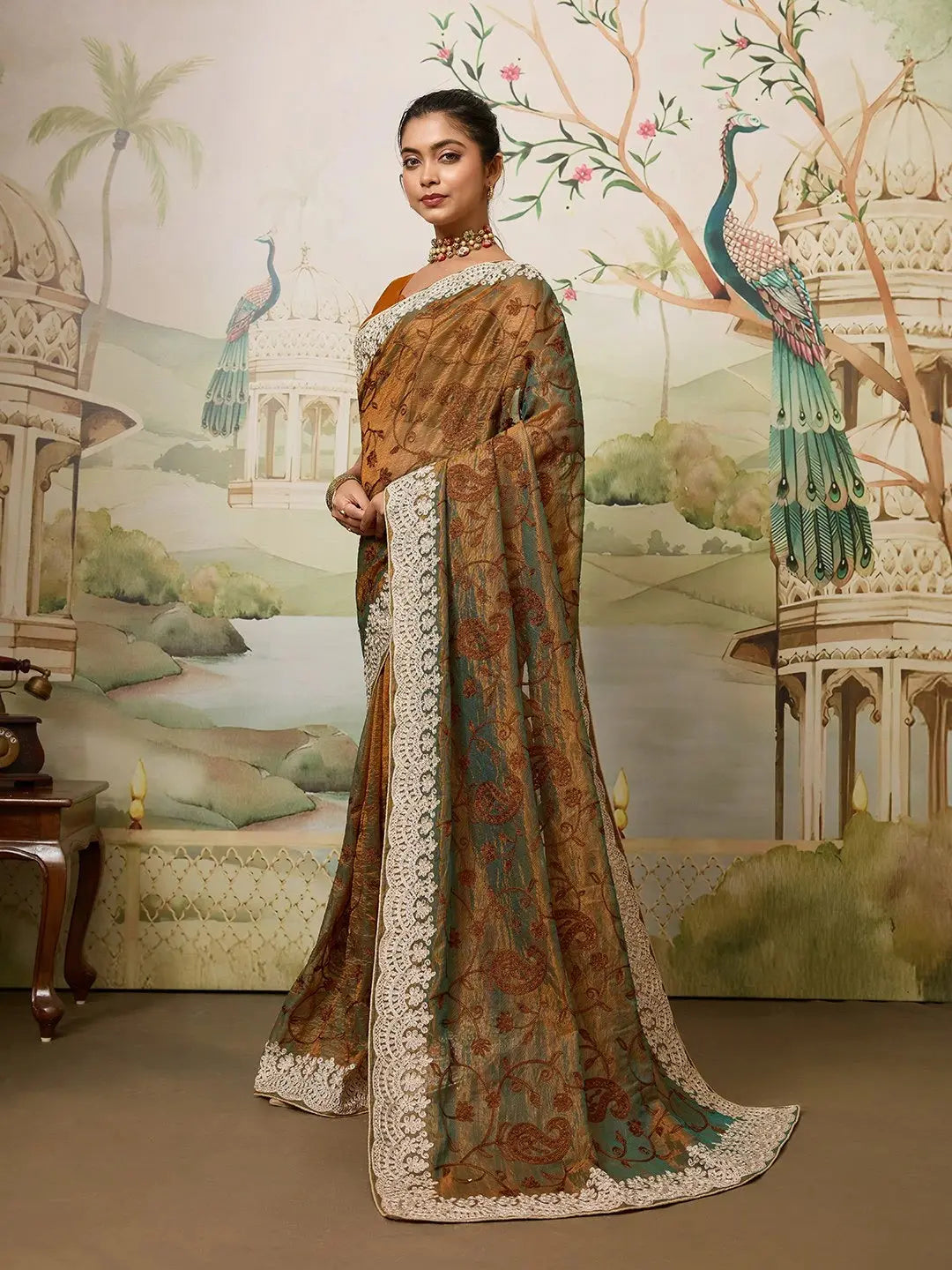 Woman in a traditional saree with a decorative background featuring peacocks and architectural elements.